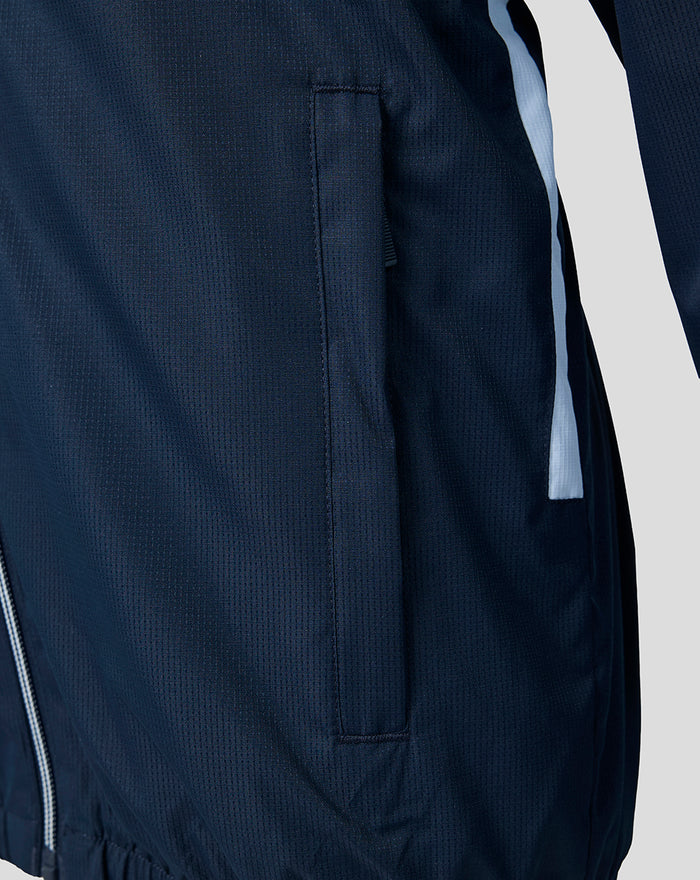 Close up of navy training jacket showing a vertical side pocket and blue detailing along the side seam.