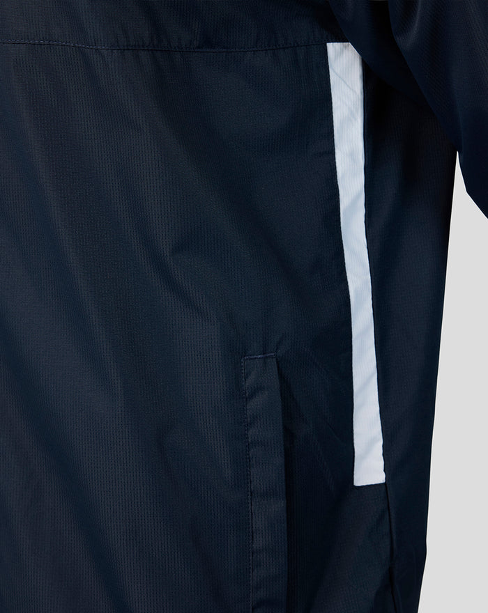 Close-up of navy training jacket fabric with a light blue vertical stripe beside a side pocket.